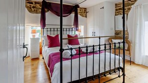 Ein Himmelbett mit Vorhängen, weiße Bettwäsche und rote Kissen.