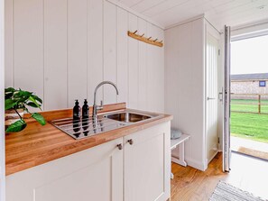 Eine Küche mit Holzarbeitsplatte, Spüle aus Edelstahl und einer Garderobe.