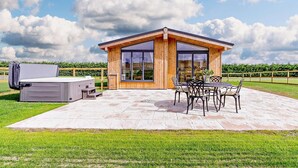 A modern wooden cabin with a patio, outdoor seating, and a large window. - 2 Bed in St. Andrews (oc-93229) (St Andrews)