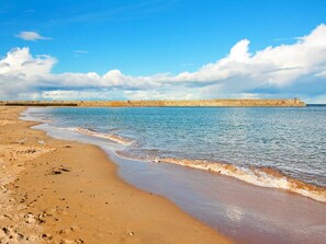A sandy beach with gentle waves, a clear sky, and a distant stone wall. - 2 Bed in St. Andrews (oc-93230) (St Andrews)