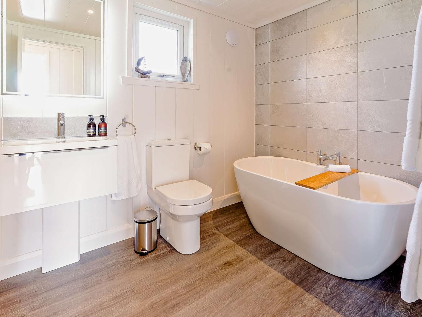 Une salle de bain moderne avec une baignoire sur pieds, des toilettes et un meuble-lavabo avec un miroir.