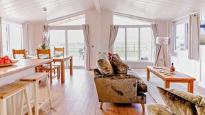 A spacious living area with a wooden dining table, a sofa, and a painting on a stand. - 2 Bed in St. Andrews (oc-93230) (St Andrews)