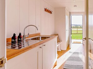 A kitchen with a wooden countertop, stainless steel sink, and a view of a grassy field through an open door. - 2 Bed in St. Andrews (oc-93230) (St Andrews)