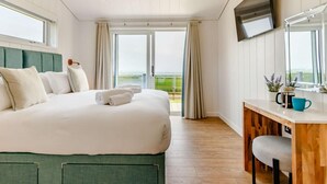 Habitación de hotel con cama, escritorio, televisión y vistas al exterior.