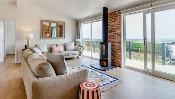 Un salón amplio con un sofá grande, una chimenea y vistas al campo a través de puertas correderas.