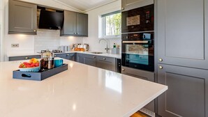 Una cocina moderna con gabinetes grises, una isla central y electrodomésticos integrados.