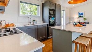 Una cocina moderna con una isla central, electrodomésticos integrados y un ventanal grande.