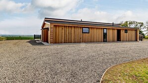 Een houten gebouw met een grindpad, een klein raam en een deur.