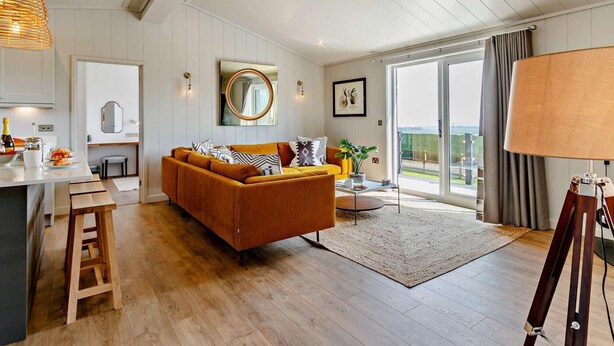 Een moderne woonkamer met een bank, een eethoek en een groot raam met uitzicht.