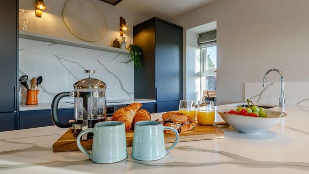 A modern kitchen with a coffee maker, croissants, and fruit bowl. - 2 Bed in Arbroath (oc-84649) (Carmyllie)