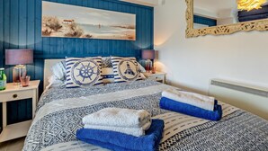 Ein Schlafzimmer mit einem Bett, einem großen Spiegel, einem Gemälde und einer ungewöhnlichen Leuchte.