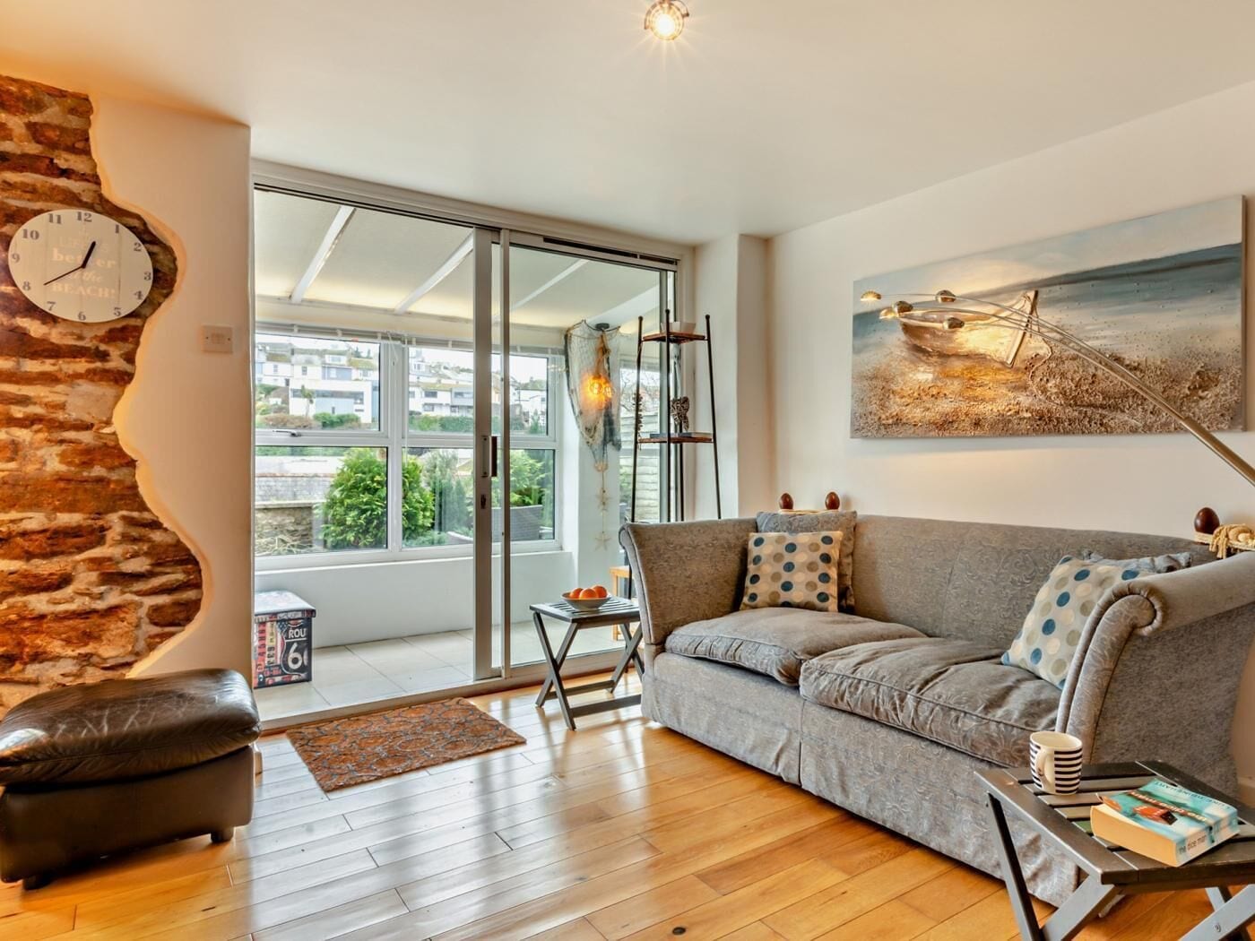A modern living room with a sofa, a coffee table, a clock on the wall, and a painting.
