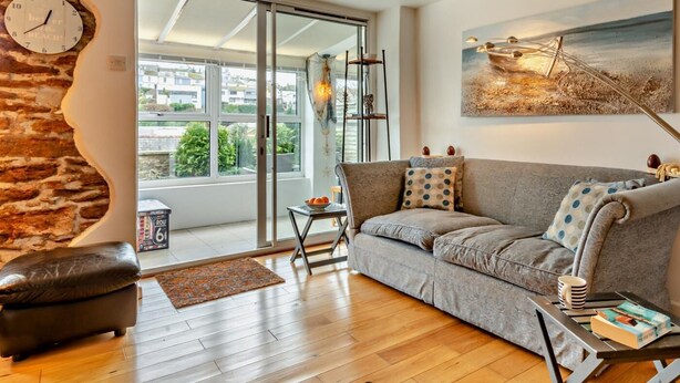 Ein modernes Wohnzimmer mit einer Couch, einem Couchtisch, einer Wanduhr und einem Gemälde.