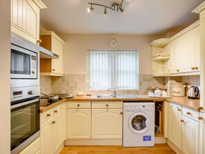 A compact kitchen with a built-in oven, microwave, and a washing machine. - 2 Bed in Hawkshead (oc-llh60) (Hawkshead)