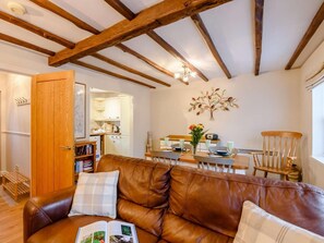 A cozy living room with a brown leather sofa, a dining area with a wooden table and chairs, and a kitchen in the background. - 2 Bed in Hawkshead (oc-llh60) (Hawkshead)