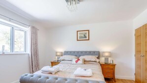 Um quarto com cama, mesas de cabeceira, janela e guarda-roupa.
