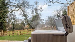 A hot tub outdoors with a wooden fence and trees in the background. - 2 Bed in Chipping Campden (oc-78128) (Chipping Campden)