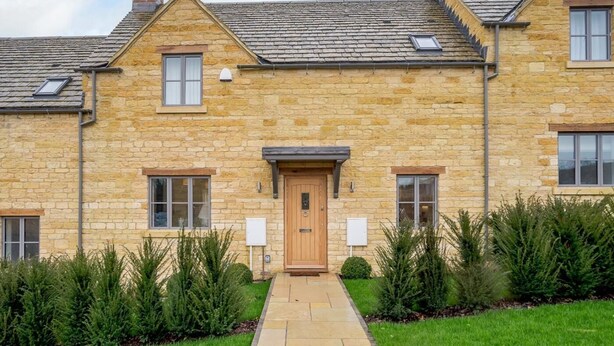 A stone building with a central entrance, two chimneys, and a small window on the upper floor. - 2 Bed in Chipping Campden (oc-78128) (Chipping Campden)