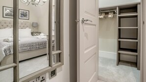 A bedroom with a bed, a chandelier, a bedside table, and a mirror. - 2 Bed in Chipping Campden (oc-78128) (Chipping Campden)