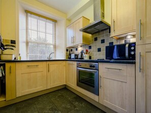 A kitchen with wooden cabinets, a microwave, an oven, and a window with blinds. - 1 Bed in Keswick (oc-sz046) (Keswick)