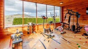 A gym with various exercise equipment, large windows, and a view of the countryside. - 3 Bed in Perth (oc-82831) (Abernyte)