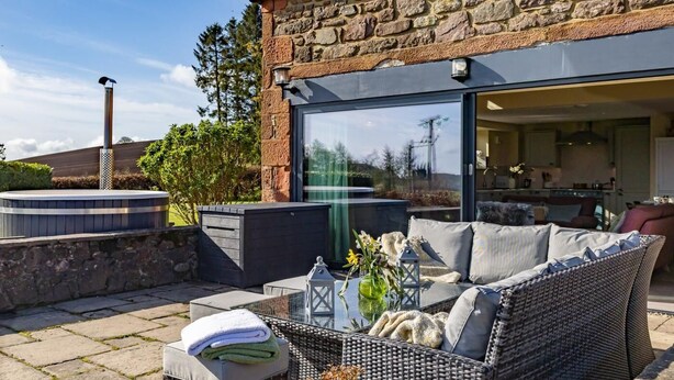 A stone building with a glass door, outdoor seating, and a hot tub. - 3 Bed in Perth (oc-82831) (Abernyte)