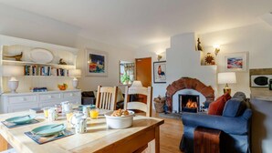 Ein gemütliches Wohnzimmer mit Kamin, ein Essbereich mit Holztisch und eine Sitzecke mit blauem Sofa.