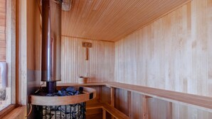 Eine Sauna mit Steinofen, Holzbänken und Holzboden.
