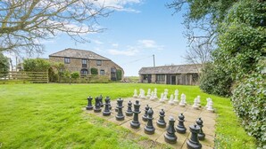 A chessboard set up in a grassy area with stone buildings in the background. - 2 Bed in Bude (oc-54244) (Poundstock)