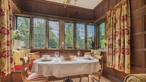 Une salle à manger avec une table ronde, des chaises et une vue dégagée grâce à de grandes fenêtres.