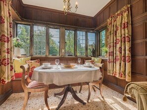 Ein Esszimmer mit rundem Tisch, Stühlen und Blick durch große Fenster.