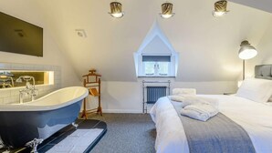 Ein Schlafzimmer mit einem großen Bett, einer Badewanne, einem Fenster und einer Heizung.