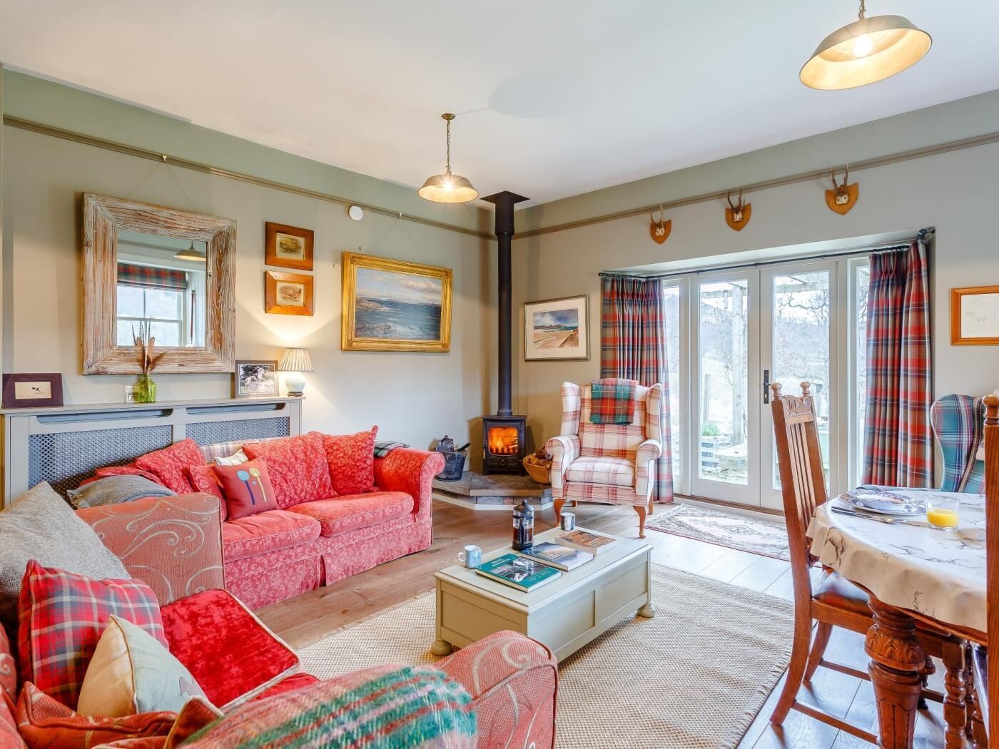 A cozy living room with a sofa, a plaid armchair, a fireplace, and a dining area with a table and chairs.