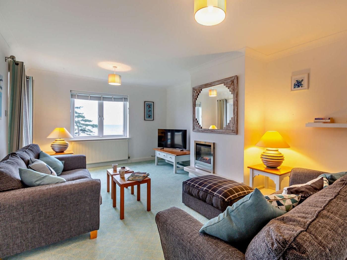 A living room with two sofas, a television, a fireplace, and a large window with curtains.
