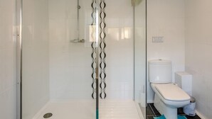 Un baño moderno con ducha de vidrio, inodoro y bidé.
