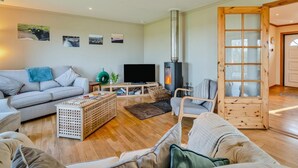 Uma sala de estar aconchegante com sofá, televisão, lareira e porta de madeira.