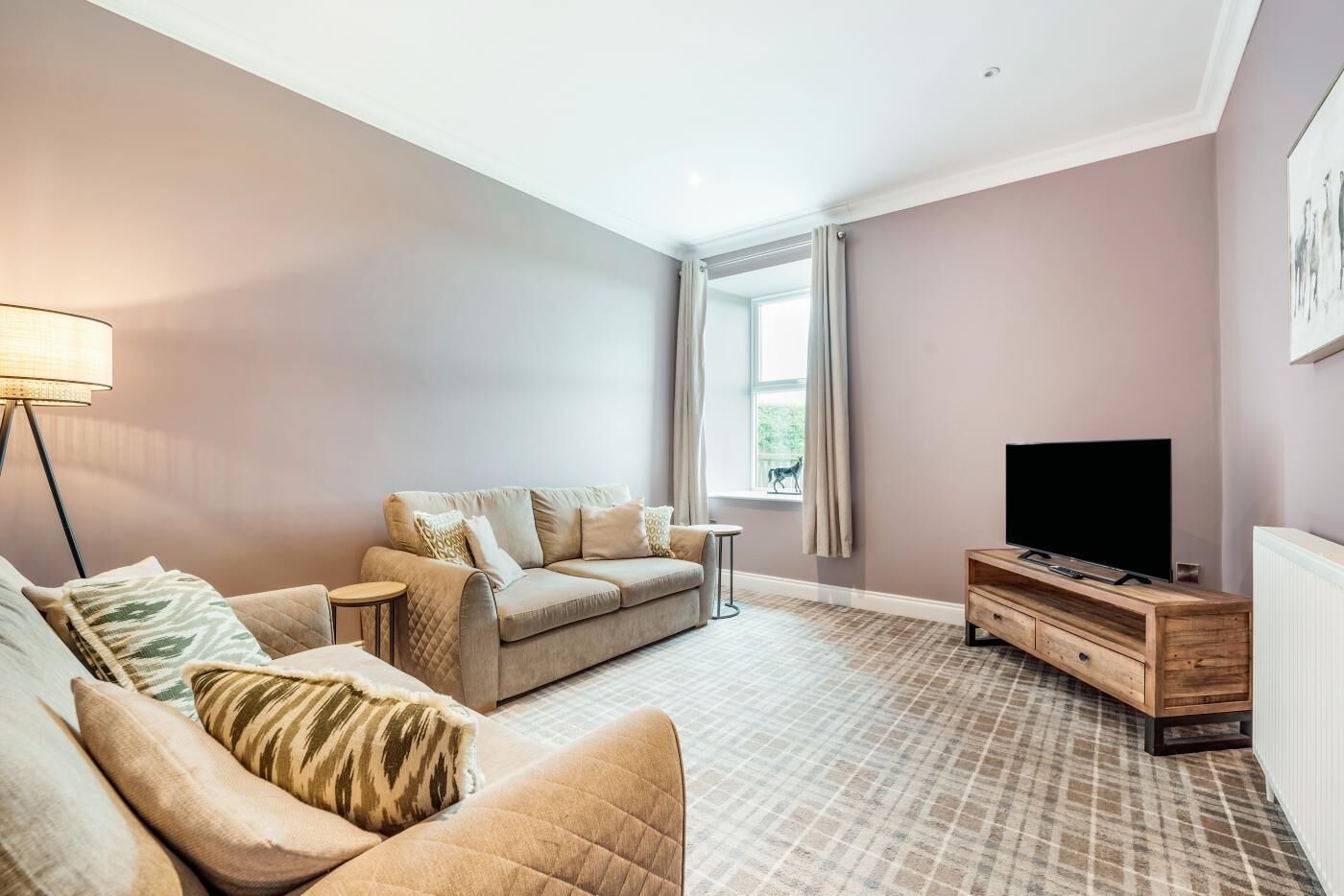Ein Wohnzimmer mit Sofa, Fernsehtisch und Lampe.