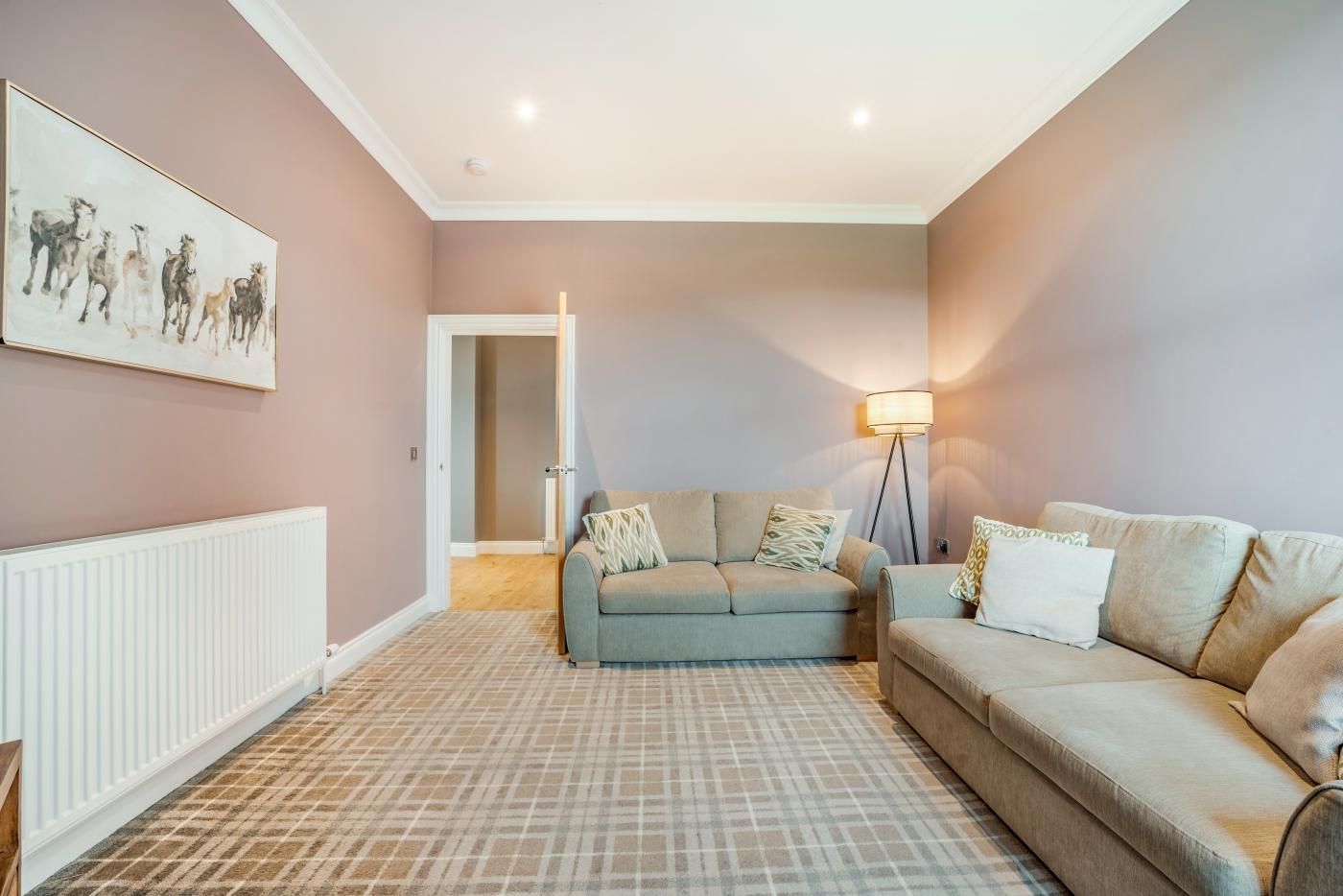 A living room with a sofa set, a floor lamp, and a painting on the wall.