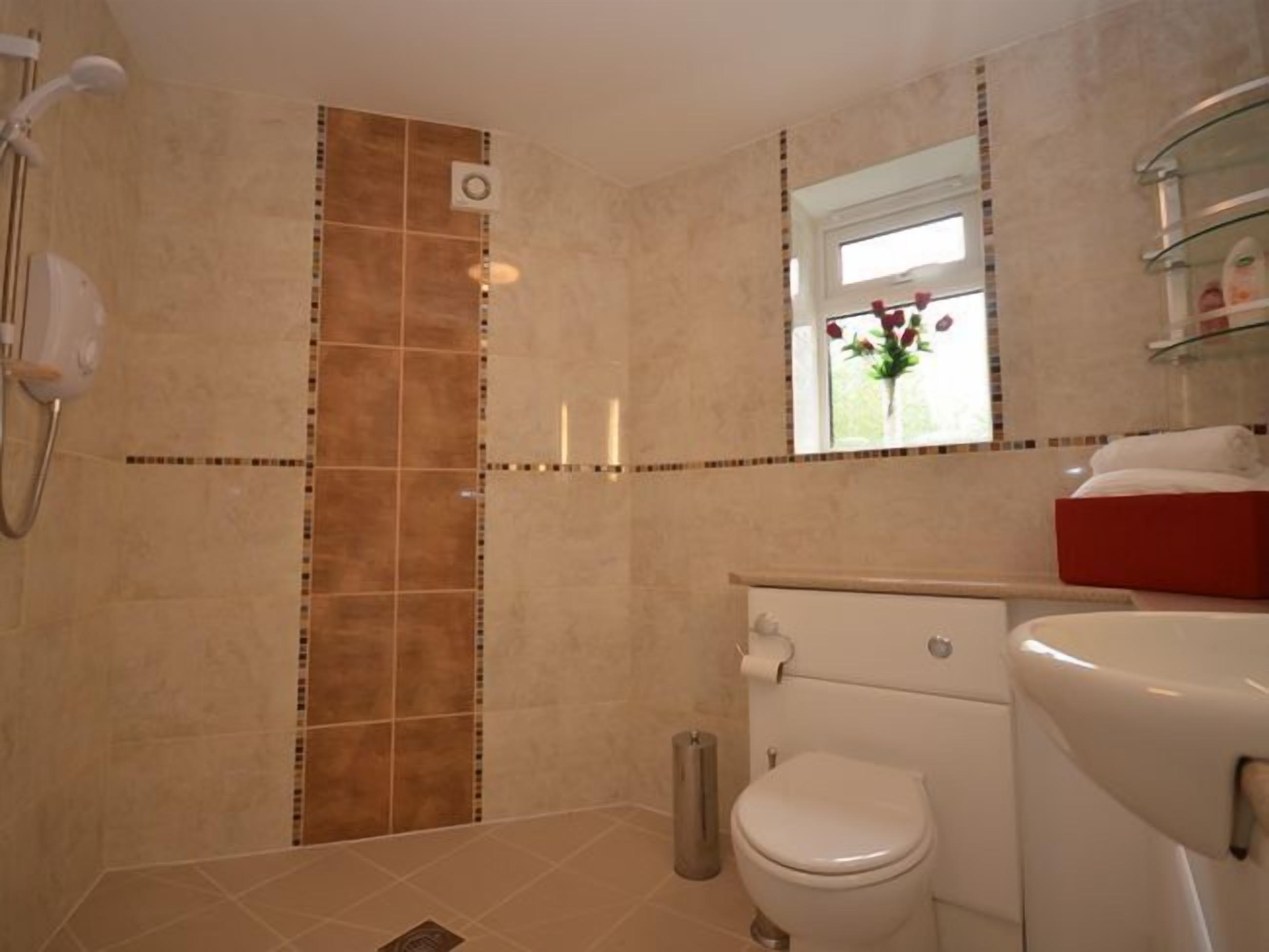 Une salle de bain avec douche, toilettes et lavabo.
