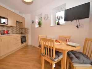 A kitchen with wooden cabinets, a red toaster, and a dining table with chairs. - 1 Bed in Newton Abbot (oc-peboo) (Caton)