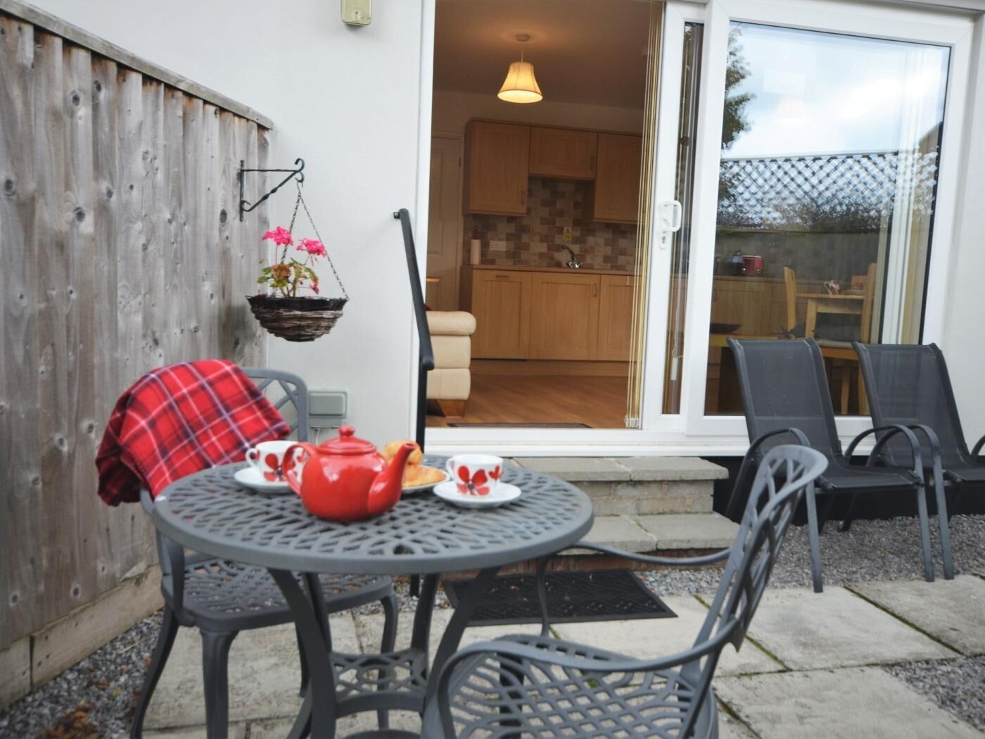 A patio with a round table, chairs, and a hanging plant.