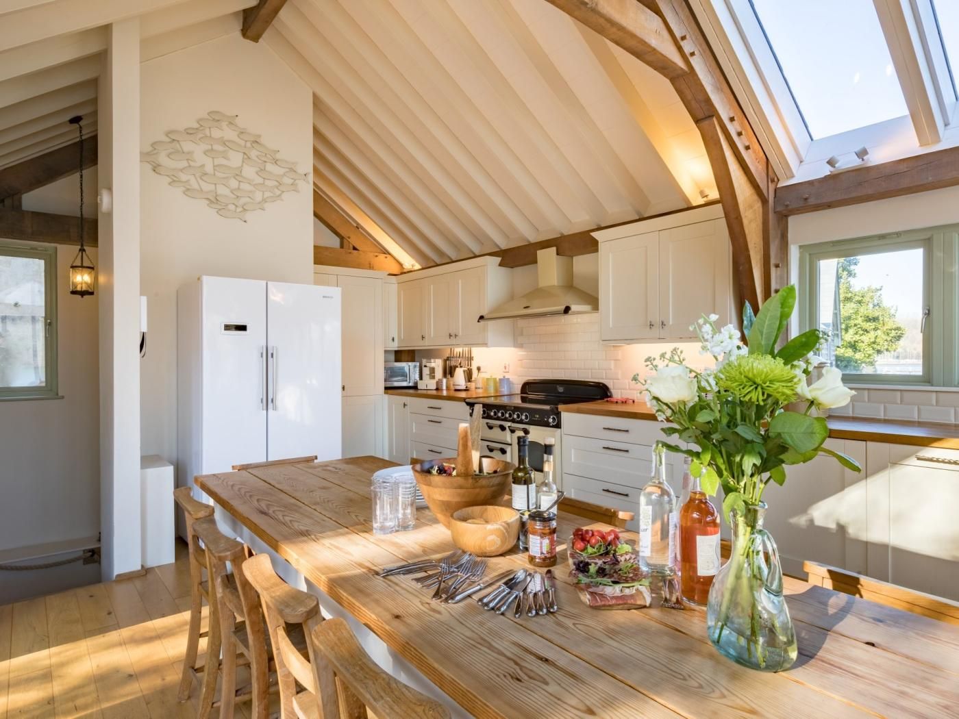 Een keuken met een houten tafel, witte kasten en een dakraam.