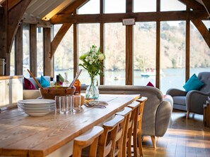 Ein Holzespeise Tisch gedeckt mit Tellern, Gläsern und einer Blumenvase, mit Blick auf einen See.