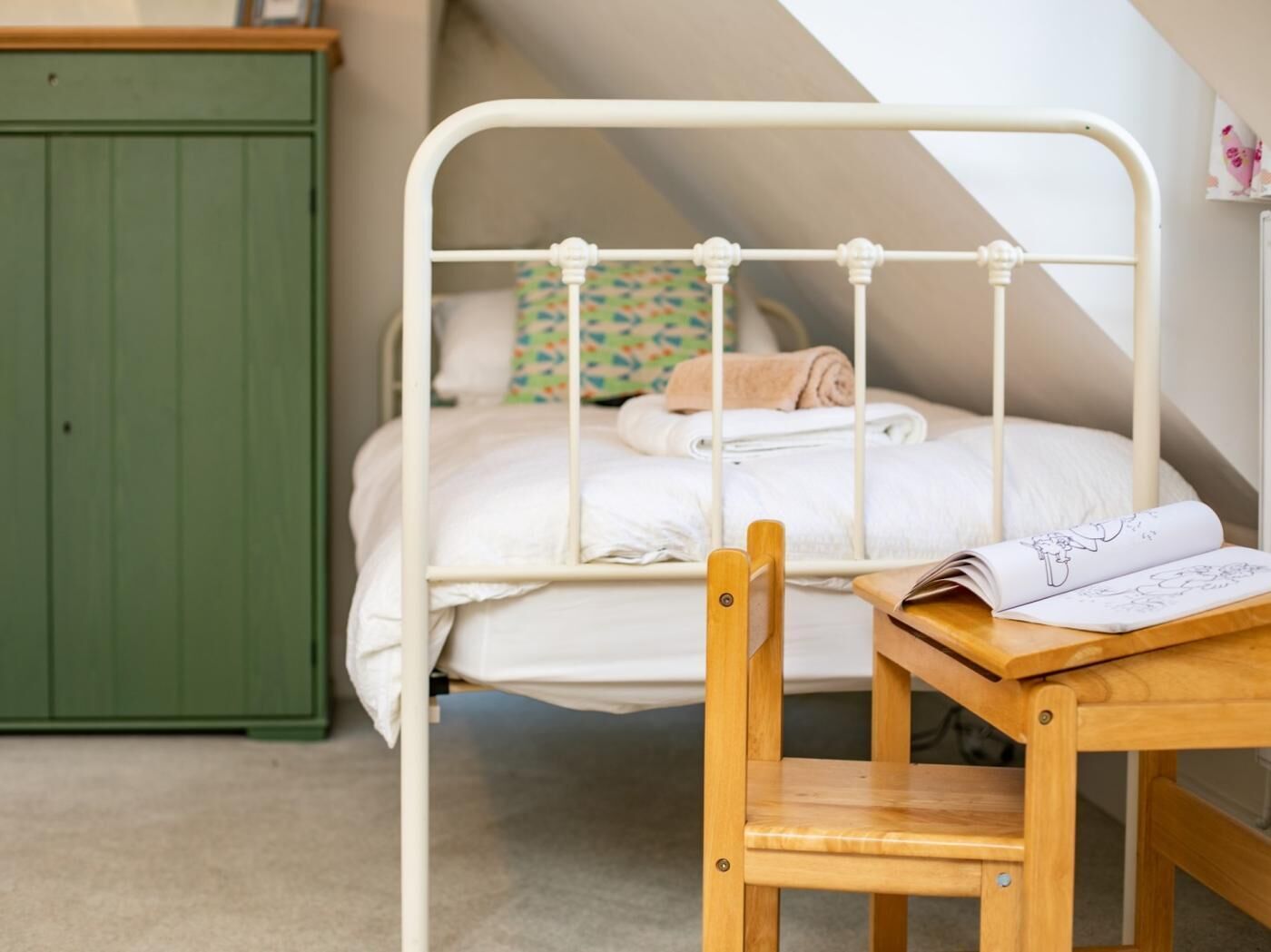 A bedroom with a bunk bed, a green wardrobe, and a wooden chair.