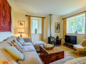 Ein gemütliches Wohnzimmer mit einer Couch, einer Holzkiste, einem Fernseher und einem Kamin.