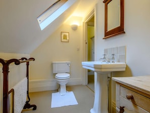 Ein Badezimmer mit Toilette, Waschbecken, Holzhandtuchhalter und einem Oberlicht.