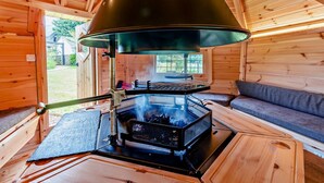 A cozy cabin interior with a wood stove, a sofa, and a window overlooking a garden. - 6 Bed in Bideford (oc-81507) (Westleigh)