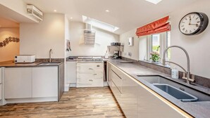 A modern kitchen with a skylight, a clock, and a window with a red valance. - 6 Bed in Bideford (oc-81507) (Westleigh)