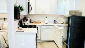 A compact kitchen with white cabinets, a black refrigerator, and a small island with a sink.