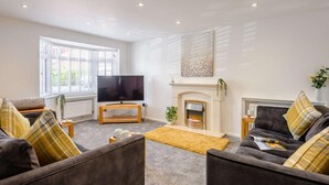 A living room with a fireplace, a television, and two sofas with plaid cushions. - 4 Bed in Christchurch (oc-87836) (Christchurch)
